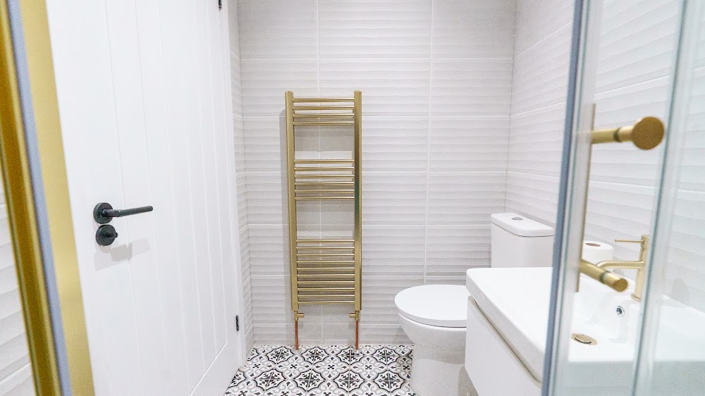 Shower room with white tiling and a brass towel rail